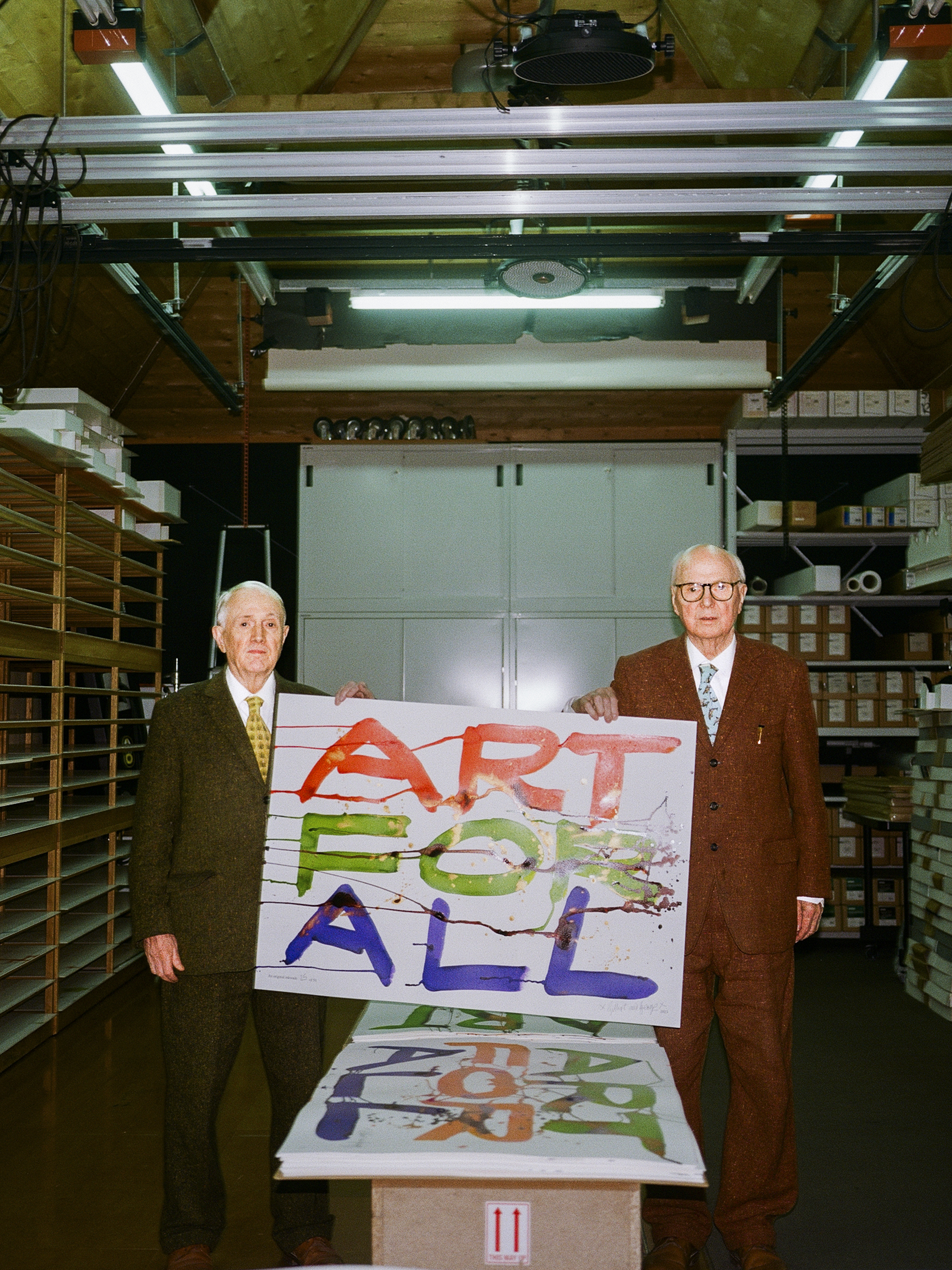 Gilbert and George holding a poster saying 'art for all'