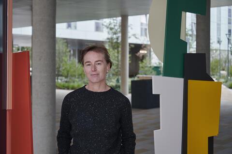 The Artist Fiona Curran standing between two public sculptures outdoors